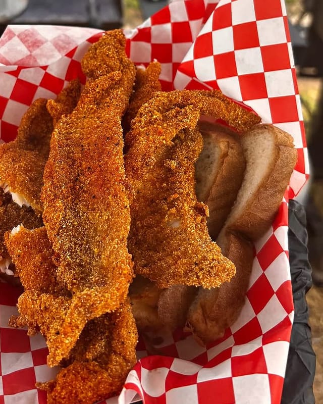 Cornmeal-fried catfish fillets with white bread in a checkered basket at a popup