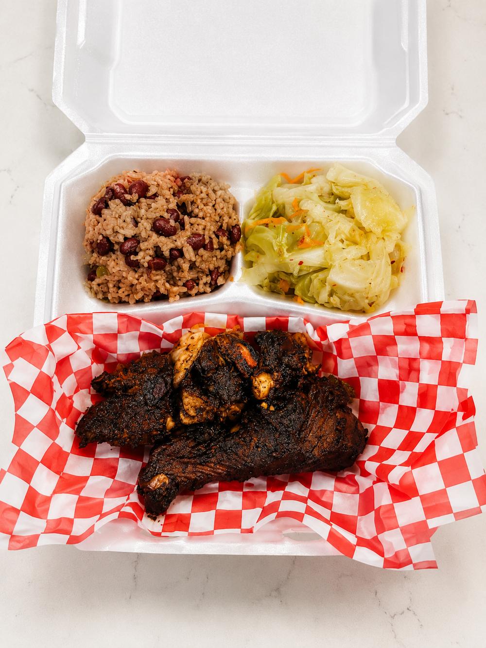 Jerk chicken with peas and rice and cabbage in a to-go box